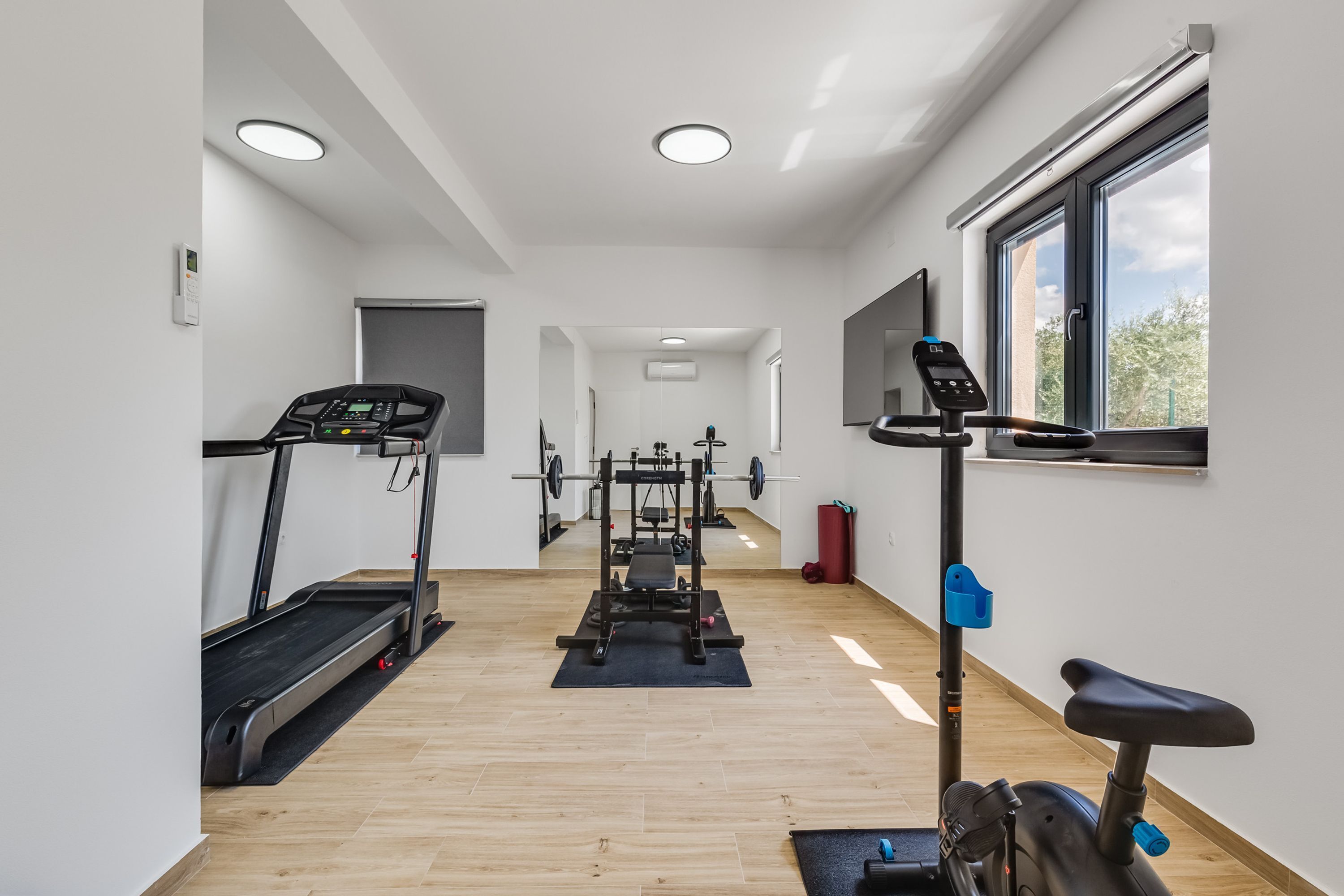 A modern gym with treadmills, a stationary bike, and a weight bench.
