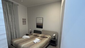 Ein modernes Hotelzimmer mit Bett, Nachttisch, Lampe und einem Gemälde an der Wand.