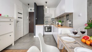 Une cuisine moderne avec des meubles blancs, un four encastré et un coin repas avec une table dressée pour deux personnes.