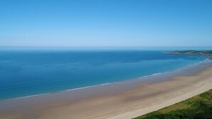 A coastal landscape with a wide sandy beach and calm sea under a clear sky. - Affinity@Pickwell Manor - huge space for 7 people. North Devon coast near Croyde (Georgeham)