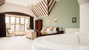 A spacious bedroom with a large bed, a wooden bench, a nightstand, and a window with curtains. - Affinity@Pickwell Manor - huge space for 7 people. North Devon coast near Croyde (Georgeham)