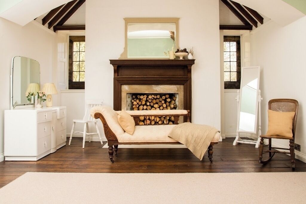 A cozy room with a fireplace, a sofa, a chair, and a dresser.