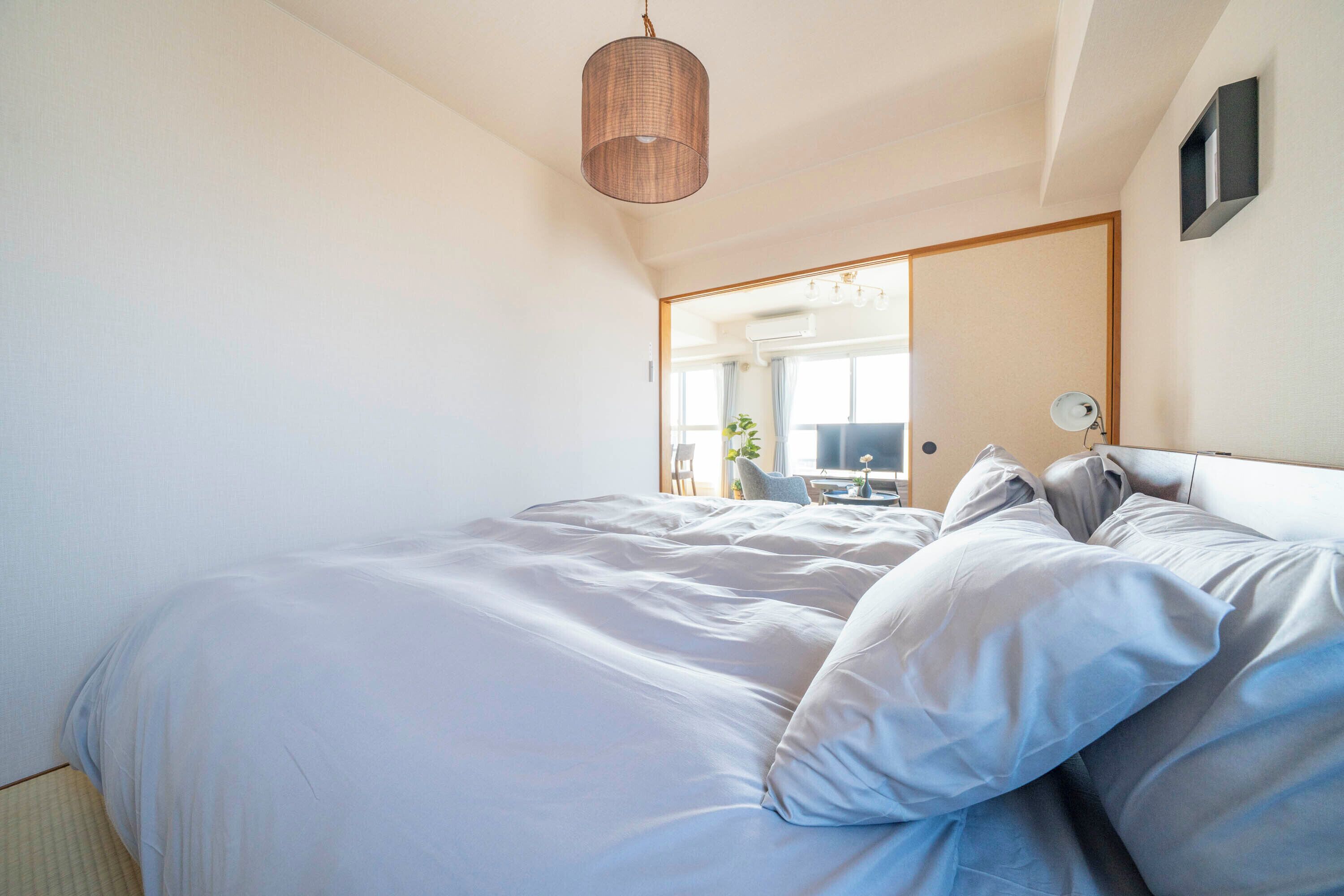 A bedroom with a large bed, a hanging light fixture, and a mirror on the wall.