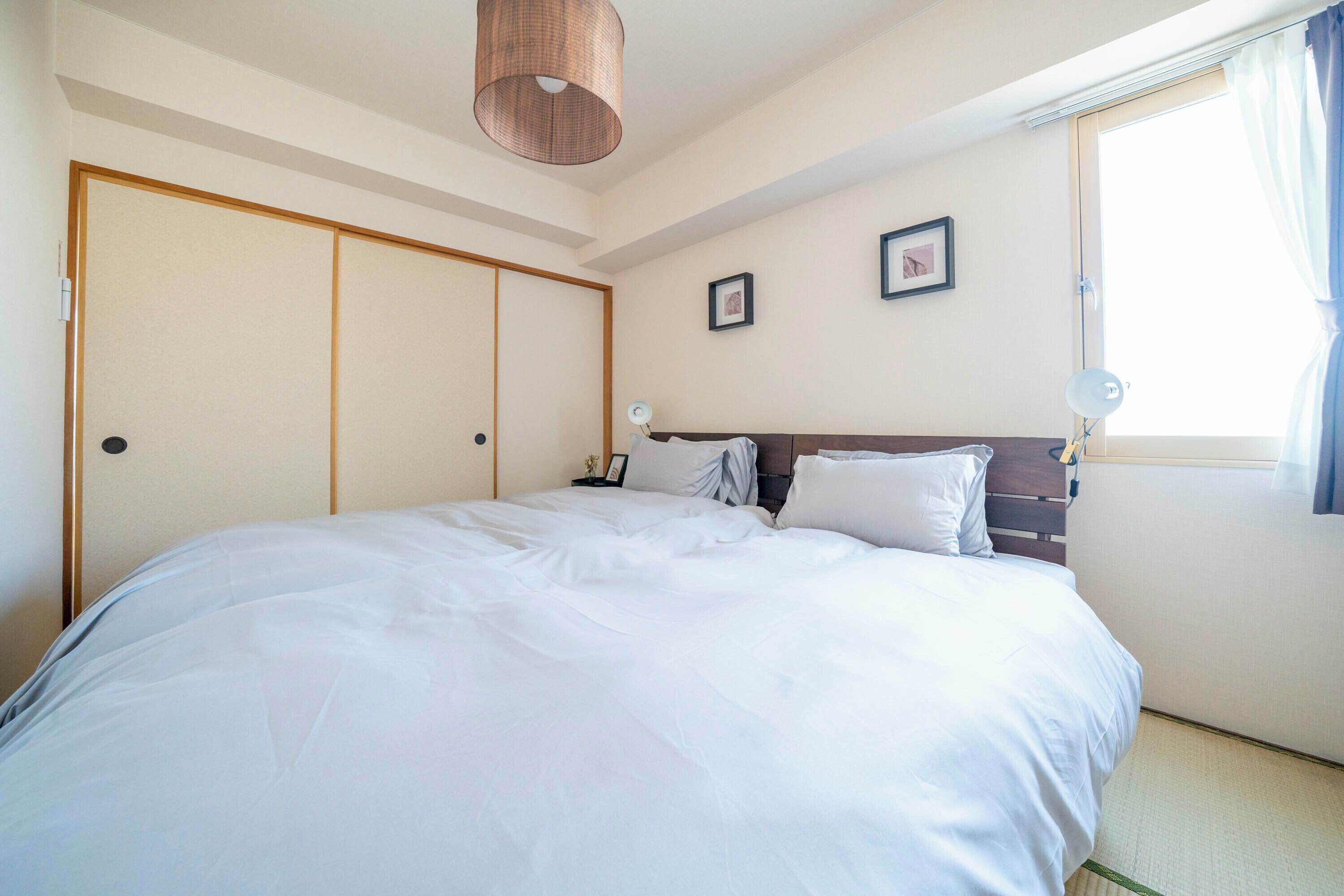 A neatly made bed with white linens, a wooden headboard, and a bedside lamp.