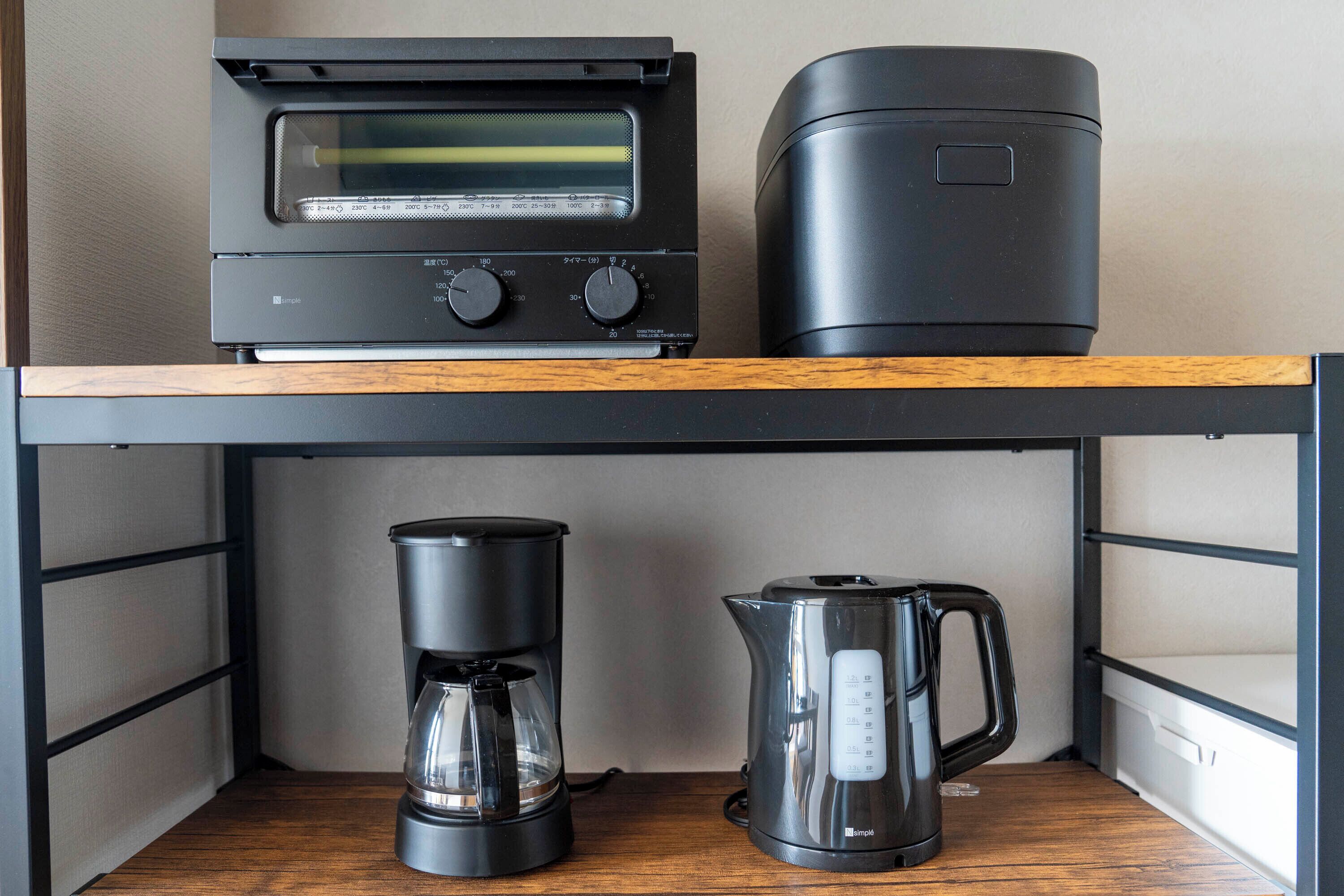 A kitchen with a coffee maker, a kettle, and a toaster oven on a shelf.