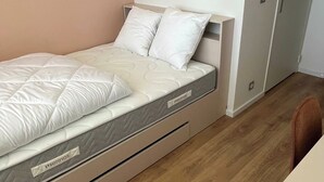 A bedroom with a bed, pillows, a nightstand, a wardrobe, and a wall-mounted picture. - Comfort Studio in a Premium Residence- Sport/cinema (Huningue)