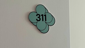 A white wall with a four-leaf clover-shaped sign displaying the number 311. - Comfort Studio in a Premium Residence- Sport/cinema (Huningue)
