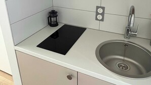 A kitchen with a stainless steel sink, a black induction cooktop, and a built-in oven. - Comfort Studio in a Premium Residence- Sport/cinema (Huningue)