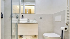 Un bagno moderno con cabina doccia in vetro, mobile bagno in legno, water e bidet.
