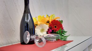Una bottiglia di vino, un bicchiere e un bouquet di fiori su un tavolo.