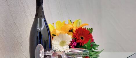 A wine bottle, a wine glass, and a bouquet of flowers on a table.