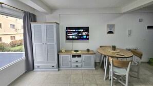 Una sala de estar moderna con comedor, televisor montado en la pared y vistas al exterior.