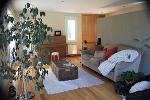 A living room with a sofa, a coffee table, a potted plant, and a window.
