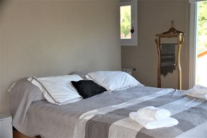 Una cama bien hecha con una colcha a rayas, un almohadón negro y dos almohadas blancas.