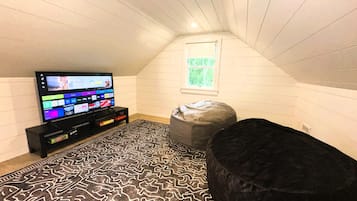A room with a television on a stand, a patterned rug, and a bean bag chair.