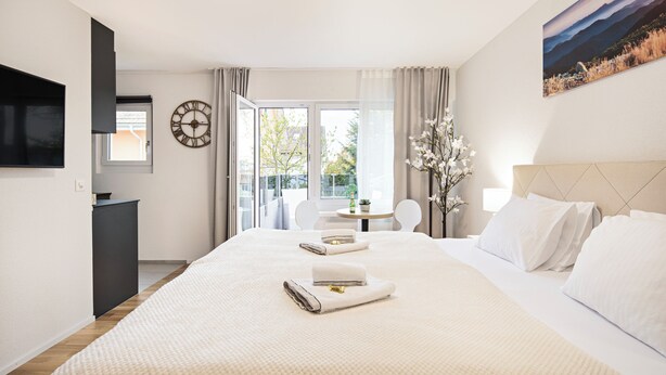 Habitación de hotel con una cama grande, televisión, escritorio y vistas al exterior.