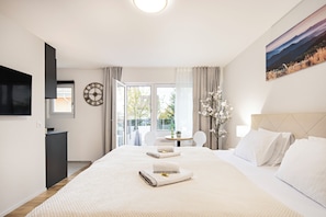 Et hotelværelse med en stor seng, et fjernsyn, et skrivebord og udsigt til det fri.