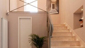A modern interior with a marble staircase, a potted plant, and a white door. - Dimorart Sant'Anna (Naples)