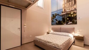 A bedroom with a bed, bedside tables, a nightstand, a large window, and a wall-mounted artwork. - Dimorart Sant'Anna (Naples)