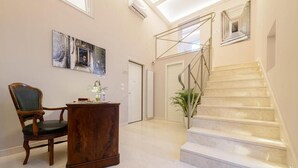 A spacious hallway with a marble staircase, a wooden chair, a desk, and a painting on the wall. - Dimorart Sant'Anna (Naples)