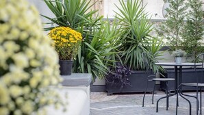 An outdoor patio area with potted plants, a seating arrangement, and a tiled floor. - Dimorart Sant'Anna (Naples)