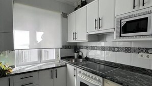 A modern kitchen with white cabinets, a black countertop, and a built-in microwave.