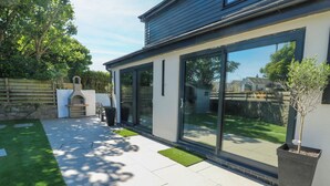 A modern house with a patio, a barbecue area, and a large sliding glass door. - Iscoed (Rhosneigr)