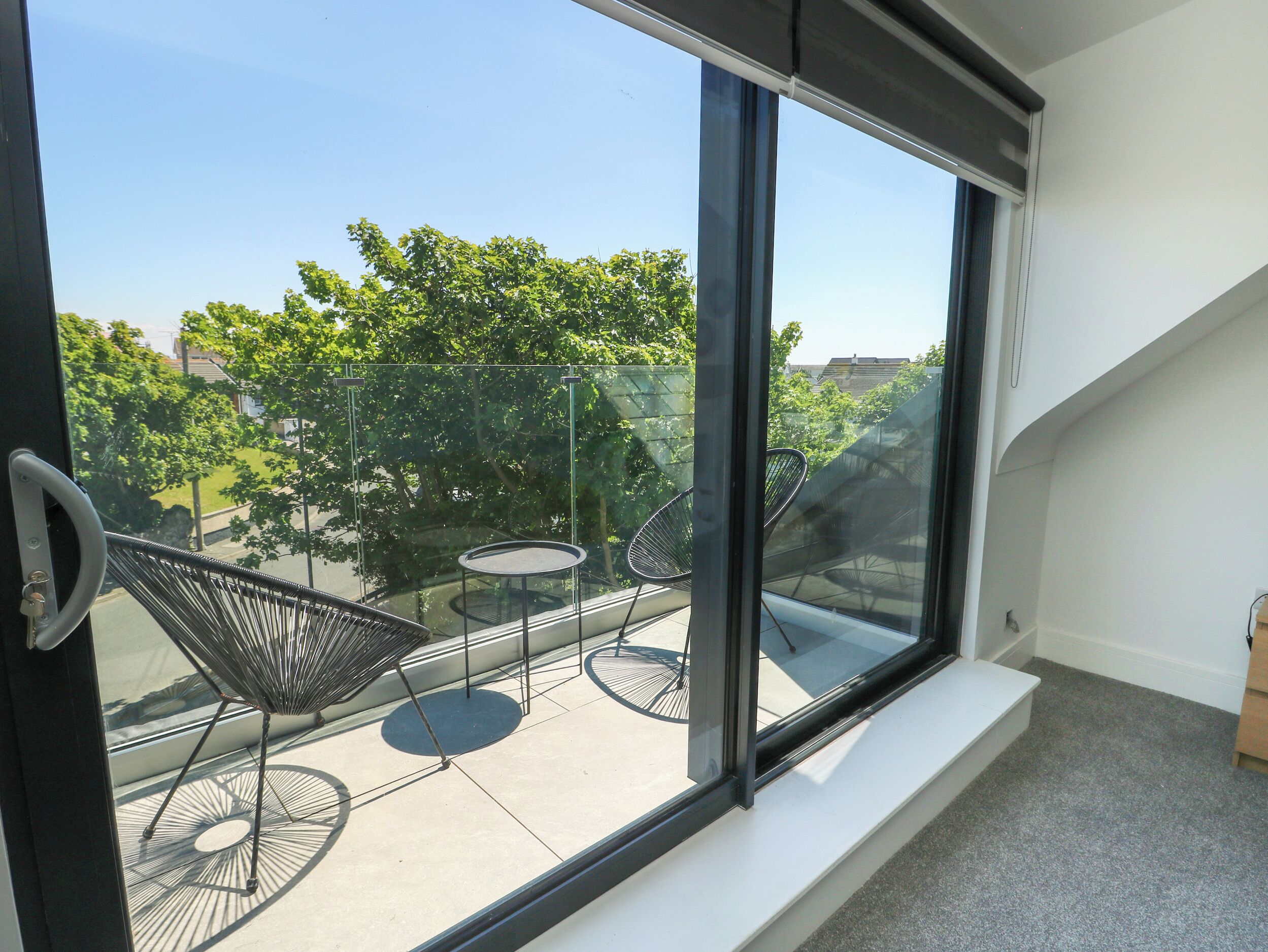 A modern room with a large window, a small round table, and two black chairs.