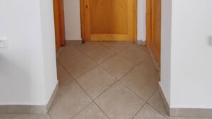 Un couloir avec une porte en bois et un sol carrelé.