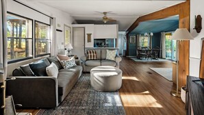 A spacious living area with a sofa, ottoman, and a dining table with chairs.
