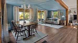 A spacious room with a dining table, chairs, a sofa, and a lamp.