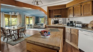 A spacious kitchen with wooden cabinets, a dining area with a table and chairs, and a view of the outdoors through large windows.
