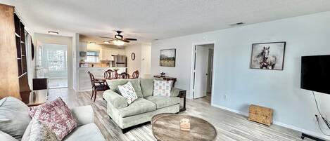 A spacious living room with a sofa, a coffee table, and a dining area with chairs.