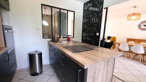 Une cuisine moderne avec un plan de travail en bois, des meubles noirs et une poubelle en acier inoxydable.