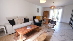 Un salon comprenant un canapé, une table basse et des fauteuils. On y trouve également un buffet en bois et une table à manger avec des chaises.