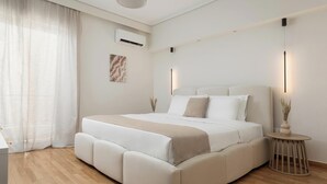 Un dormitorio moderno con una cama grande, una mesita de noche y una pequeña mesa redonda con un florero.