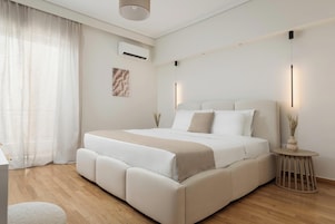 Un dormitorio moderno con una cama grande, una mesita de noche y una pequeña mesa redonda con un florero.