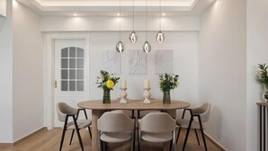 Un comedor con una mesa redonda, seis sillas, lámparas colgantes y decoración en la pared.