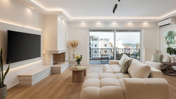 Una sala de estar moderna con un televisor de pantalla plana, chimenea, un conjunto de sofás y un balcón con vistas.