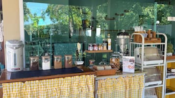 A cafe with a counter, checkered tablecloths, and various food items displayed.