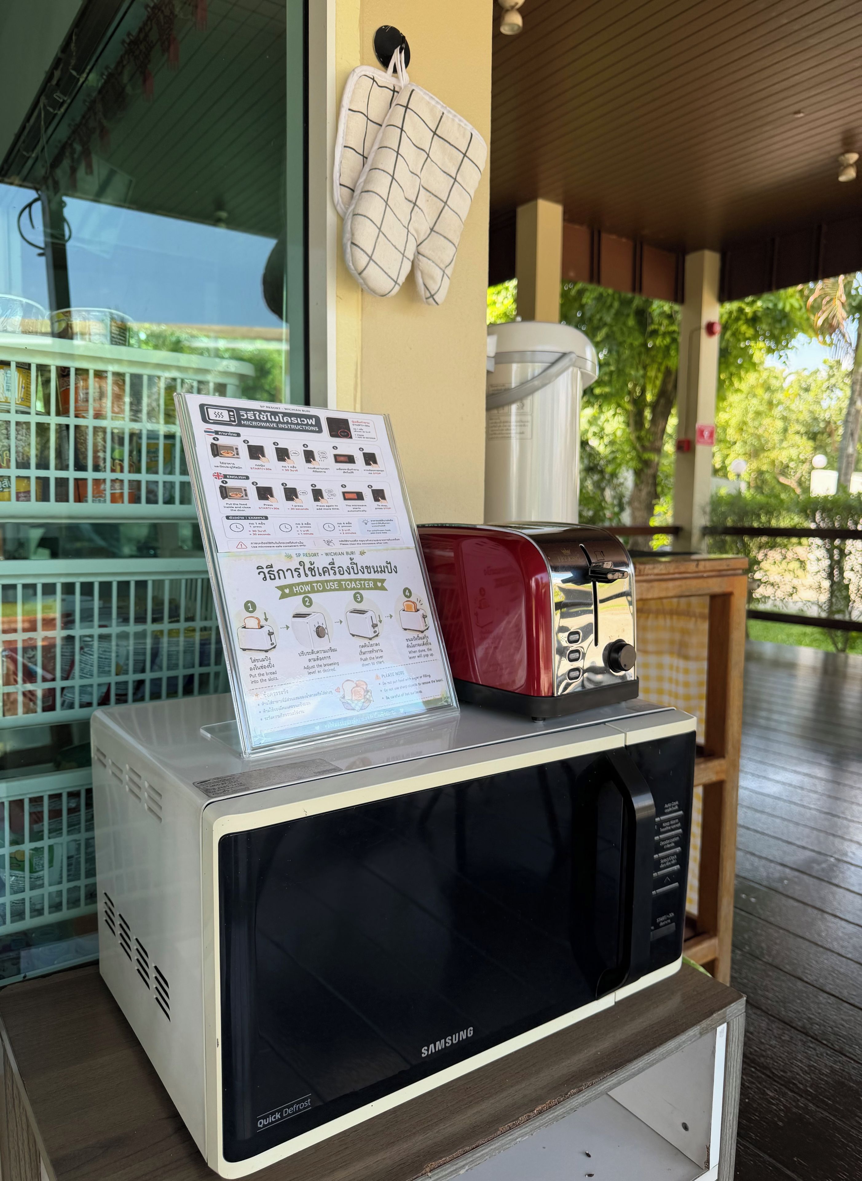 Un four à micro-ondes Samsung posé sur une table en bois, avec une étiquette indiquant la fonction de dégivrage rapide, un grille-pain et un panneau affichant les instructions.