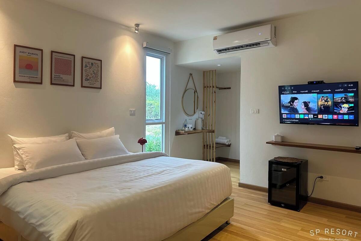 A modern hotel room with a large bed, a TV mounted on the wall, and framed artwork on the wall.