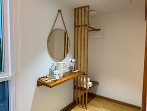 A bathroom with a wooden vanity, a mirror, a towel rack, and a toilet. - SP RESORT (Wichian Buri)