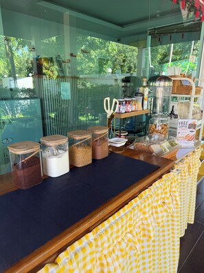 A counter with jars of food items, a coffee machine, and a sign offering free coffee and toast. - SP RESORT (Wichian Buri)