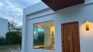 A modern building with a large window, a wooden door, and a small outdoor seating area.