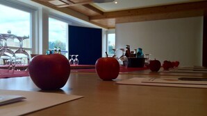 A conference room with a wooden table, red apples, and wine glasses. - Economy Hotels Kronach (Kronach)