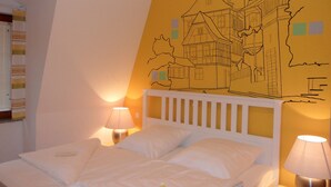 A hotel room with a bed, two bedside lamps, and a wall mural of a building. - Economy Hotels Kronach (Kronach)