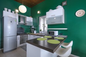 Cozinha moderna com ilha central, eletrodomésticos de aço inoxidável e paredes verdes.
