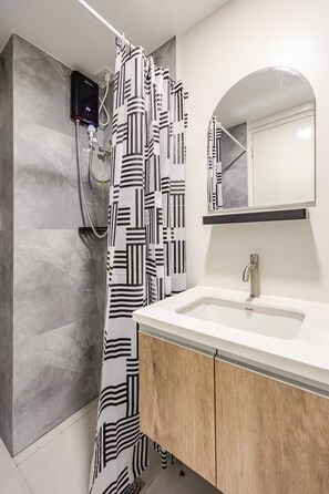 A modern bathroom with a shower, a sink, and a mirror.