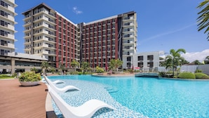 Un hotel moderno con piscina, diversi piani e un esterno dai colori rosso e bianco.